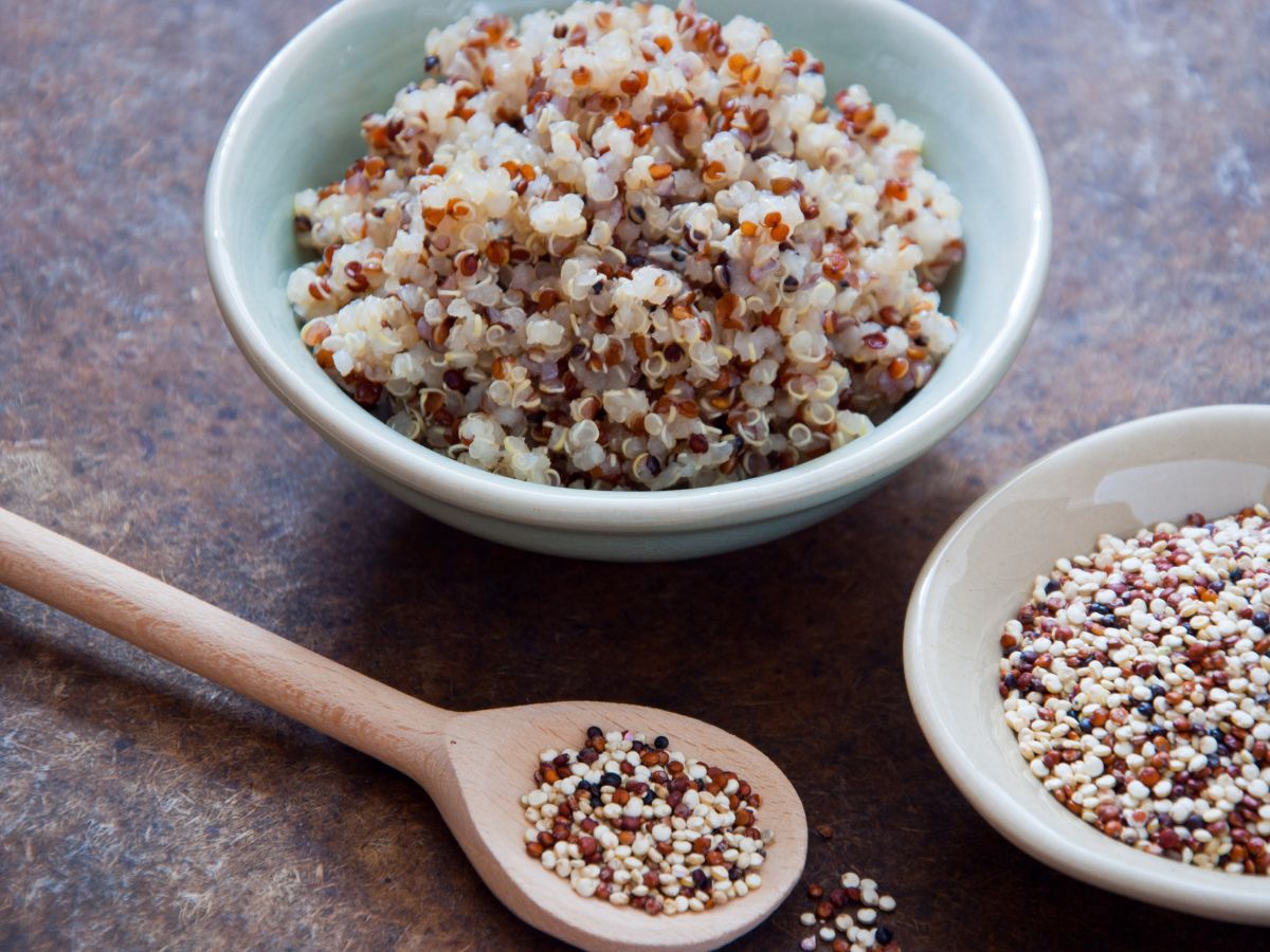 A spoon and two bowls of cooked and uncooked quinoa