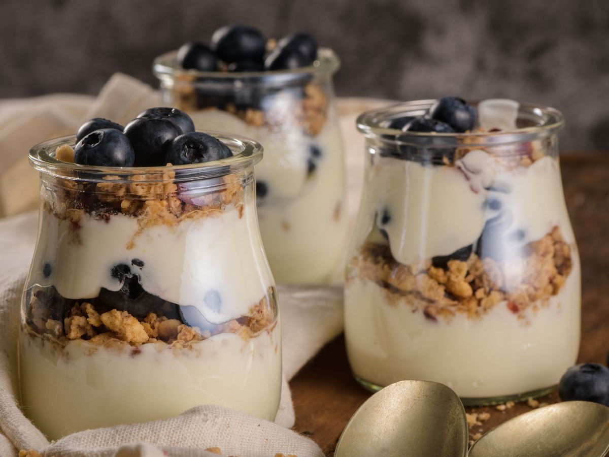 Three jars of Greek yogurt with blueberries and granola.