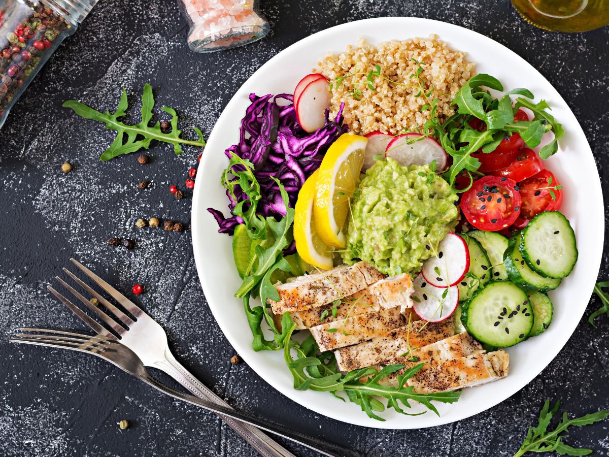Quinoa bowl with arugula, grilled chicken, vegetables, and guacamole