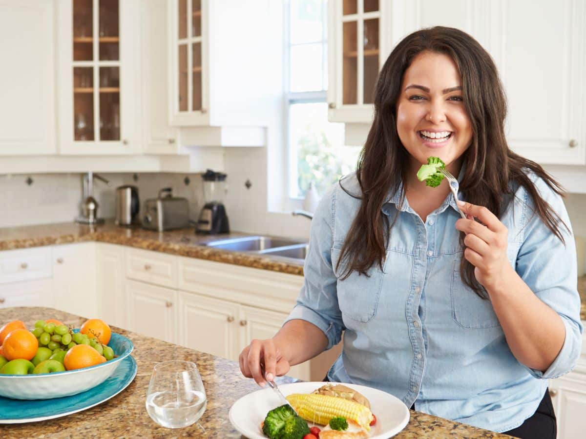Woman Eating Plate of Food in Kitchen