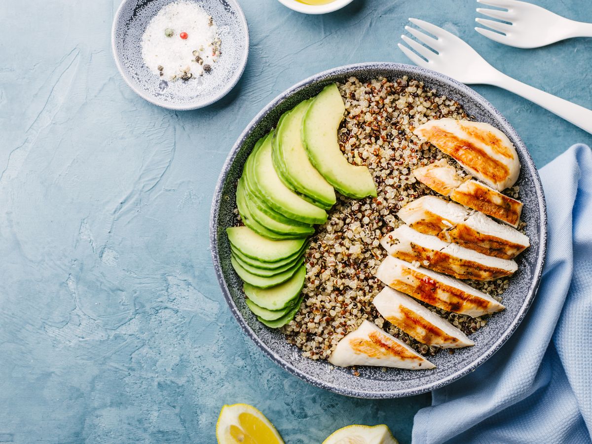 Plate of quinoa topped with sliced avocado and sliced grilled chicken