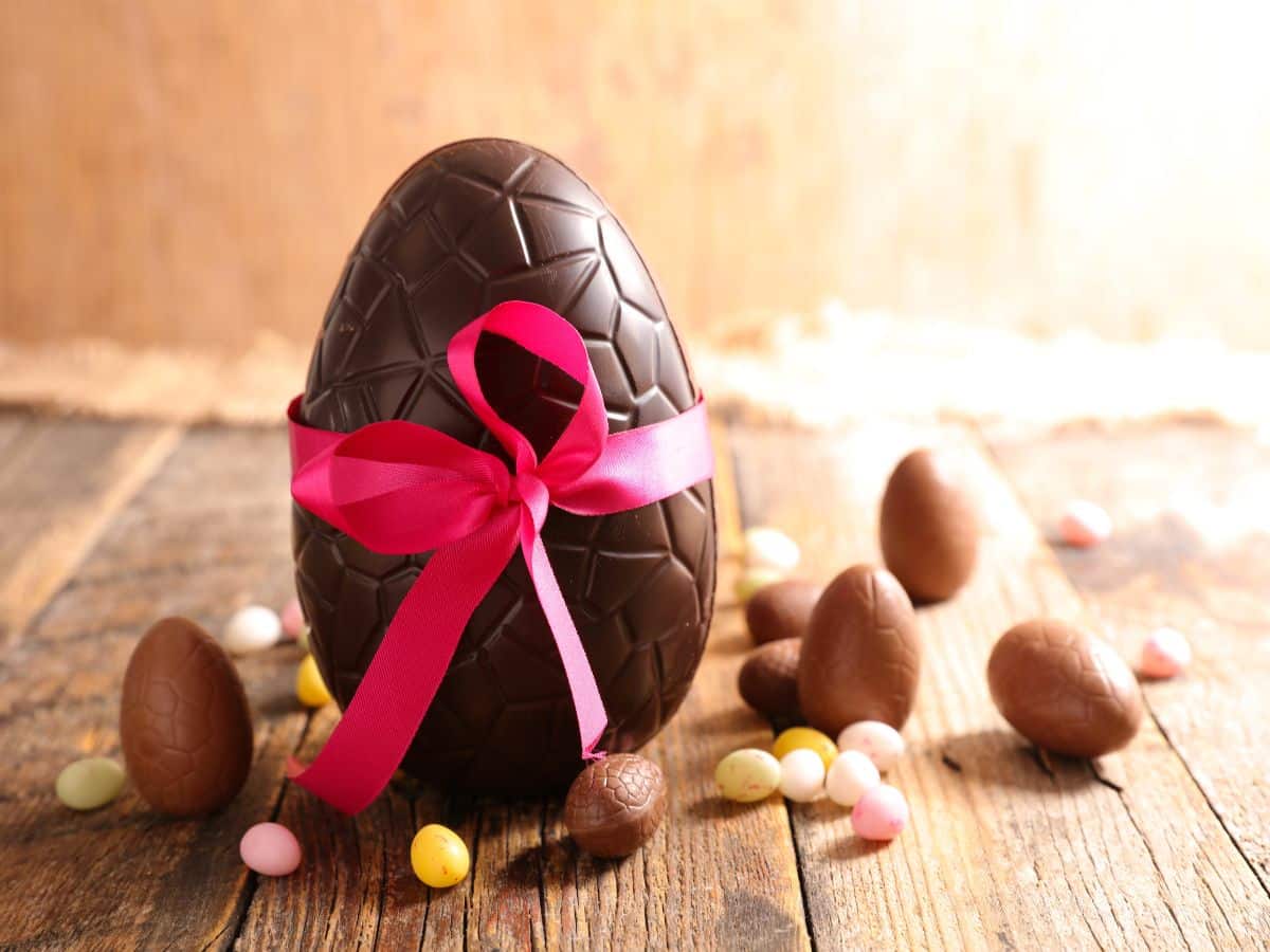 Chocolate Easter egg wrapped in pink ribbon and assorted Easter candy