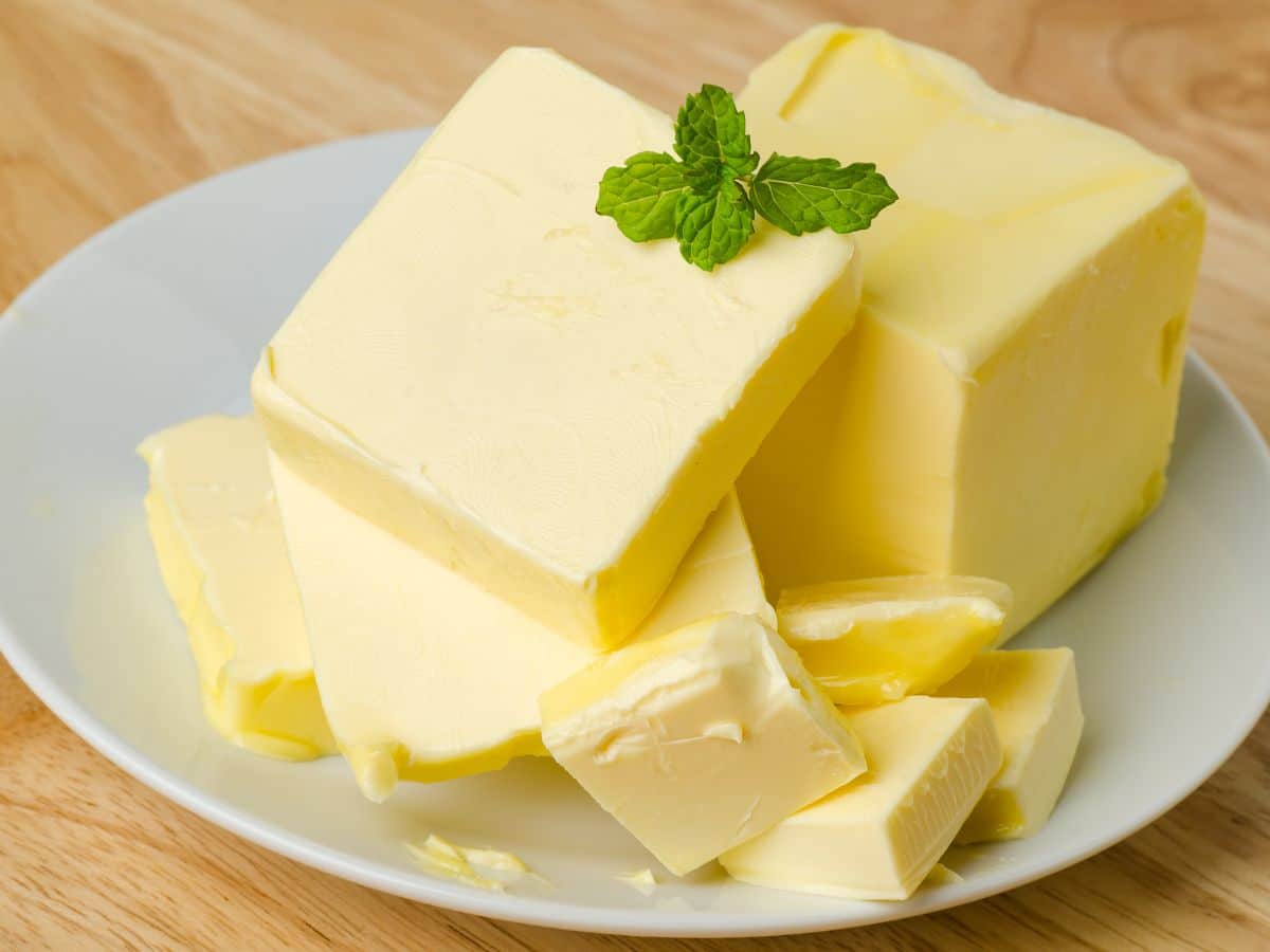 A block butter cut into slices on a white plate