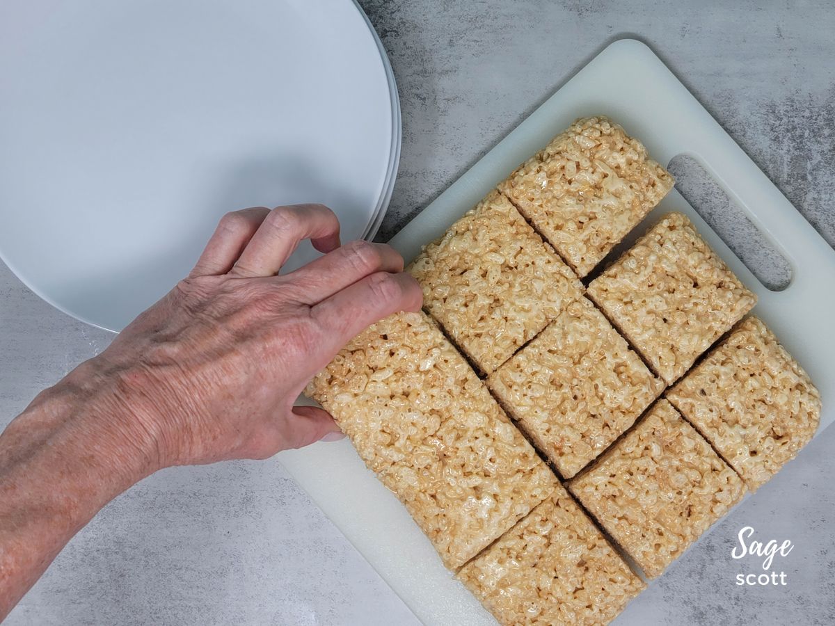 Person picking up a rice crispy square from a cutting board