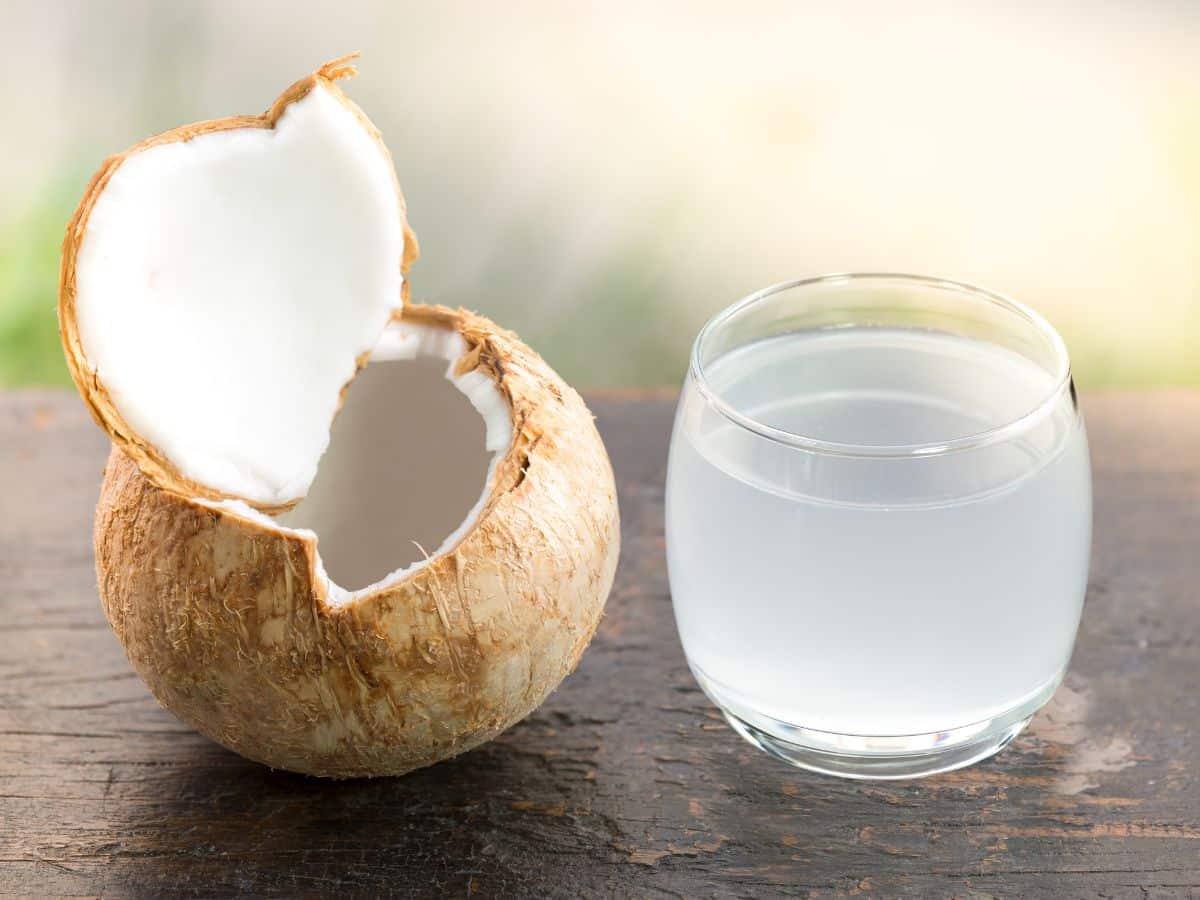 An open coconut with the water drained into a glass
