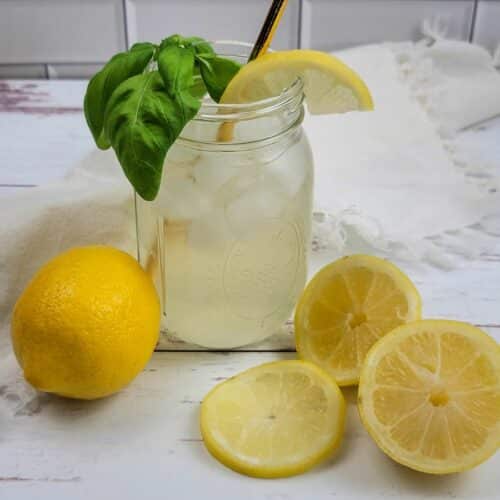 A mason jar of sugar free lemonade garnished with fresh basil leaves