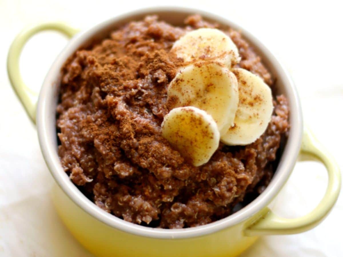 A bowl of quinoa with chocolate and banana slices on top.