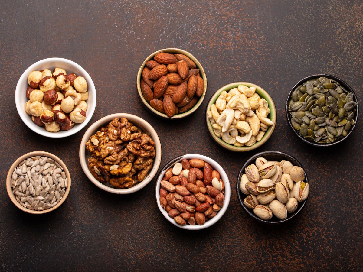 A variety of nuts in bowls on a dark background.