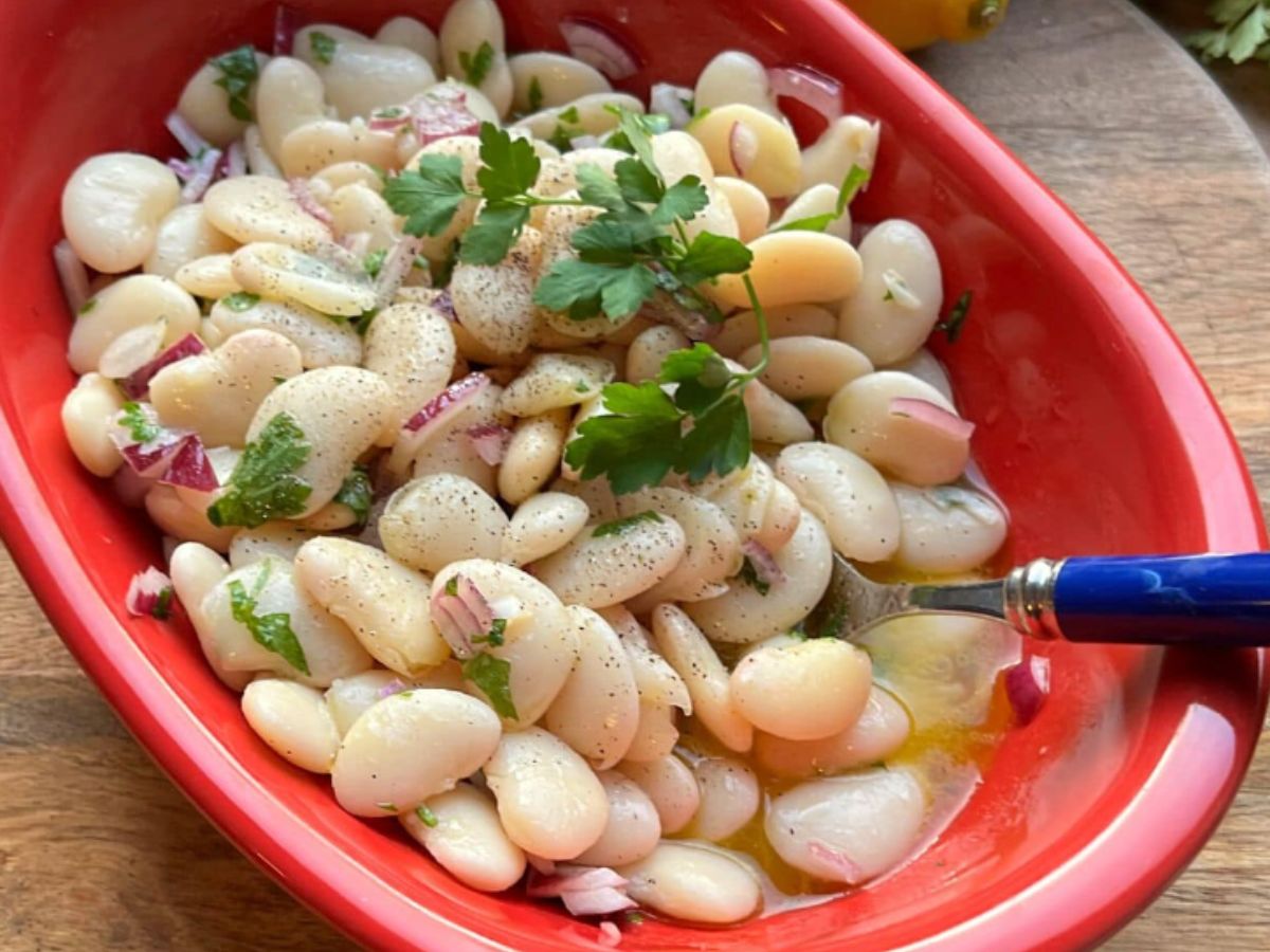 A red bowl of butter bean salad ready to serve.