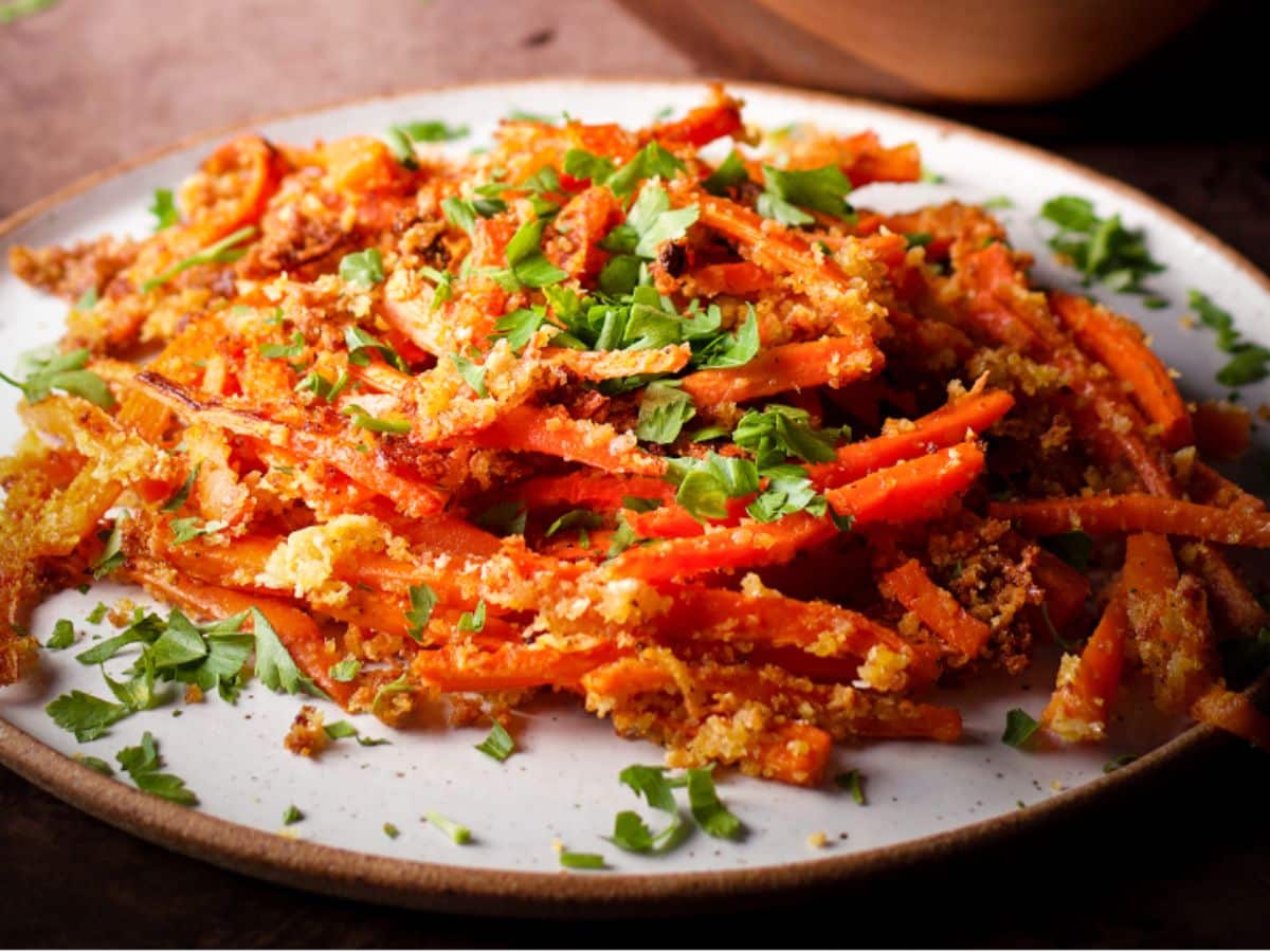 A plate of crispy carrot fries sprinkled with fresh herbs and ready to eat.