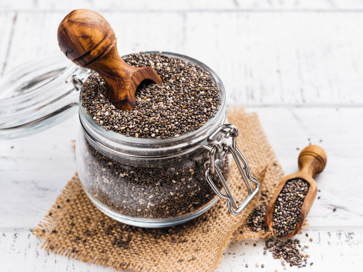 Chia seeds in a glass jar with wooden spoon, highlighting the benefits of chia seeds.