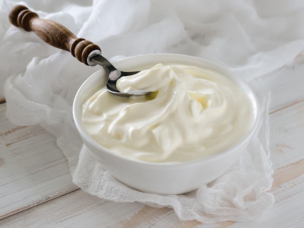 A white bowl of Greek yogurt with a spoon in it.