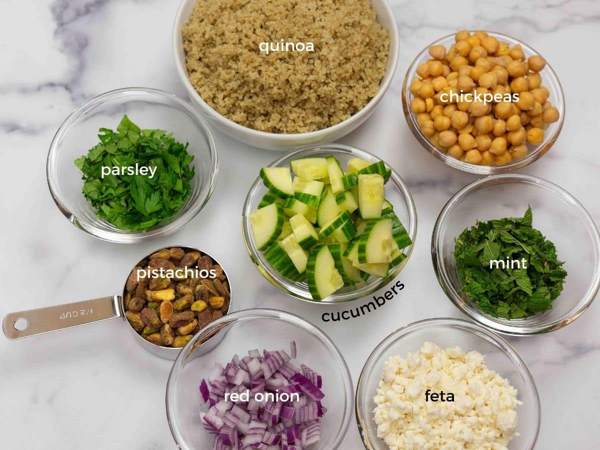 The ingredients needed to make Jennifer Aniston's favorite quinoa salad including quinoa, chickpeas, cucumbers, and fresh herbs.