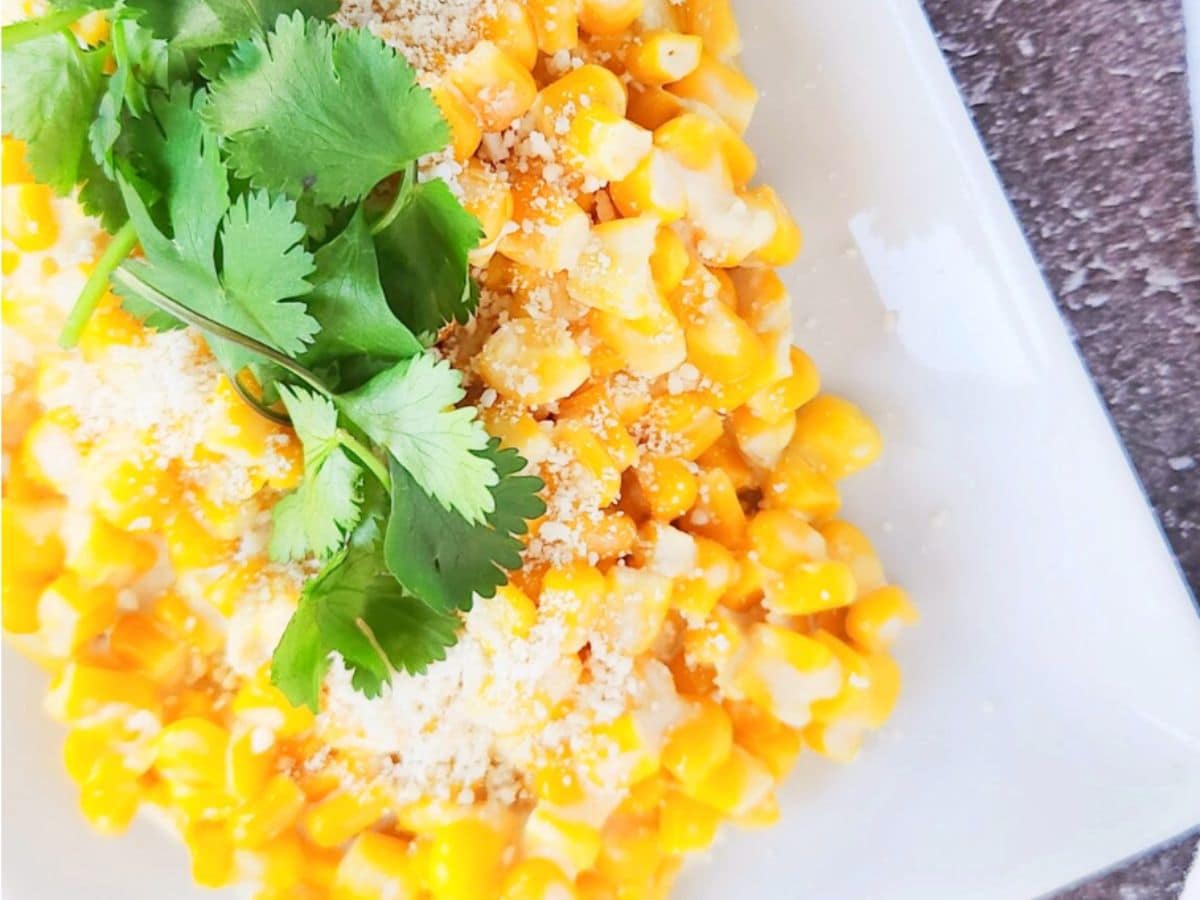 A white serving dish of Mexican street corn topped with fresh cilantro.
