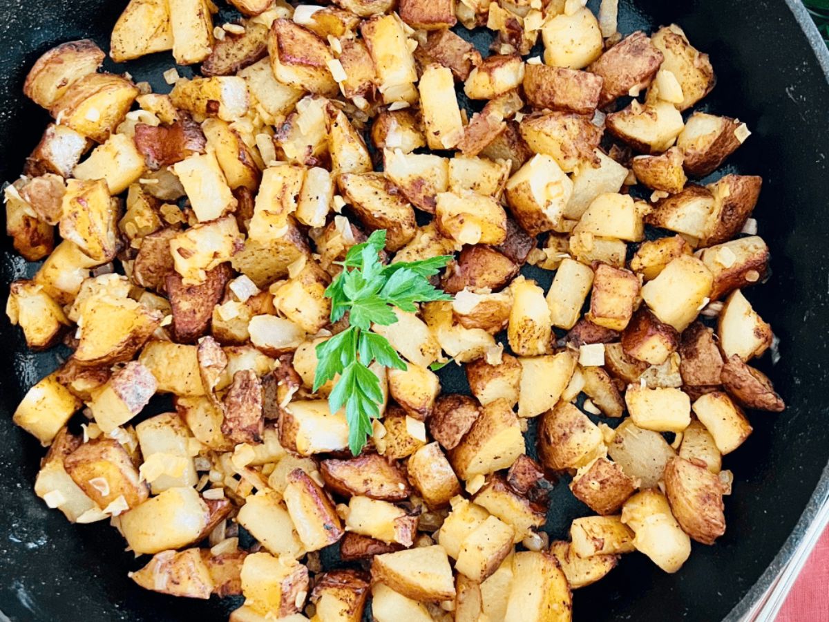 A skillet of diced potatoes fried with onions.