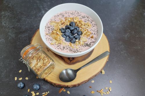 A bowl of strawberry Greek yogurt topped with blueberries and granola.