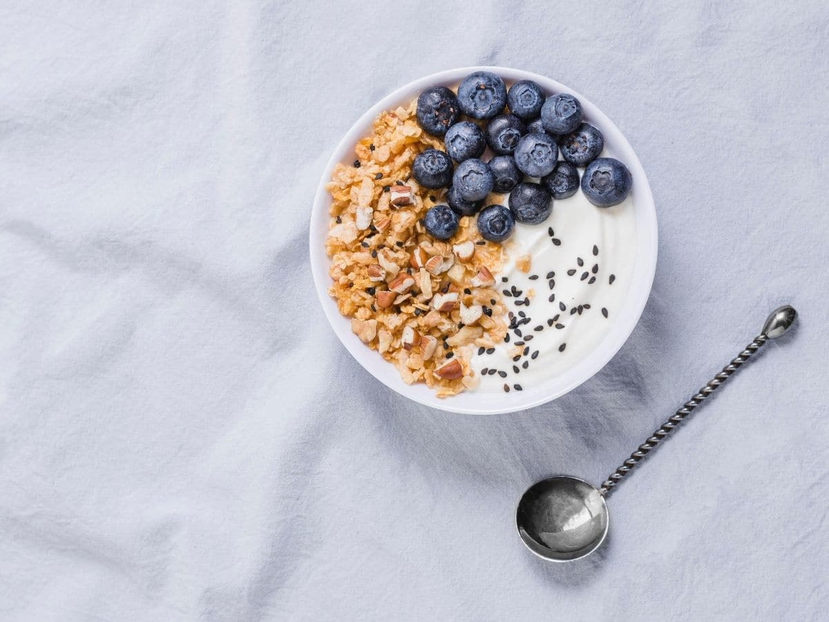 A bowl of yogurt with blueberries, granola, and chia seeds.