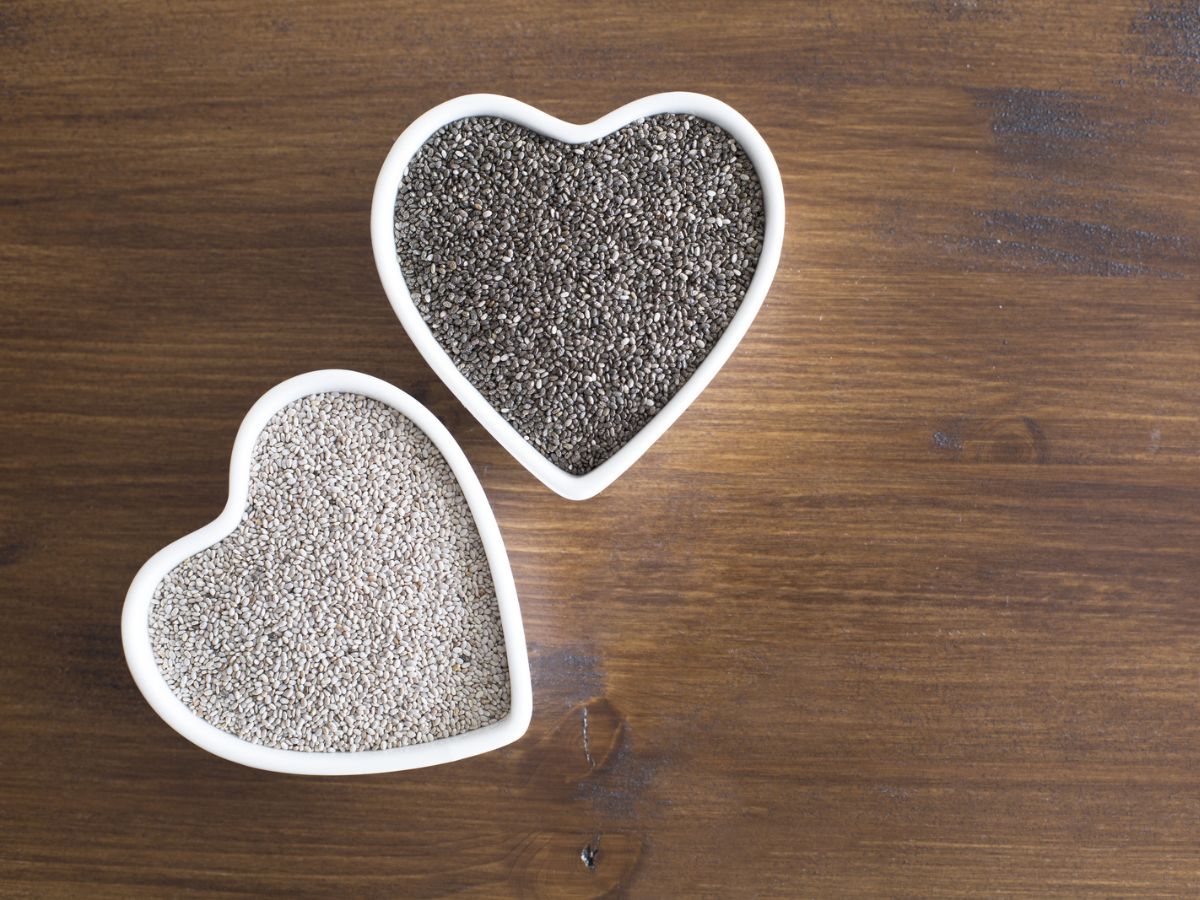 Two bowls of chia seeds in a heart shape on a wooden table.