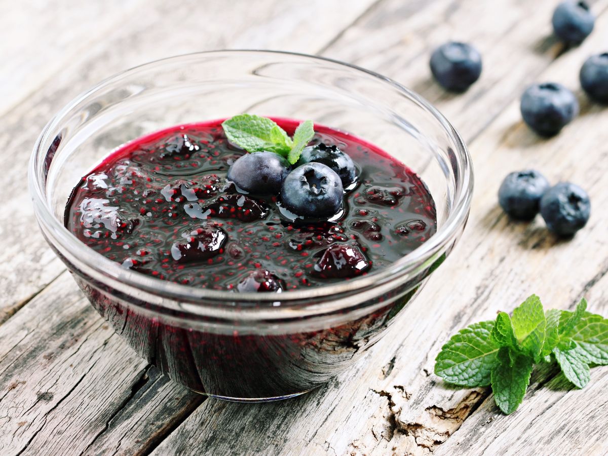 A bowl of blueberry chia seed jam on a wooden table.