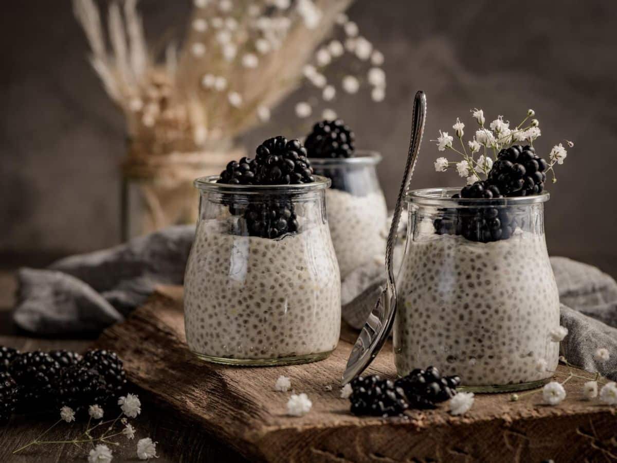 Chia pudding in jars with blackberries and flowers.