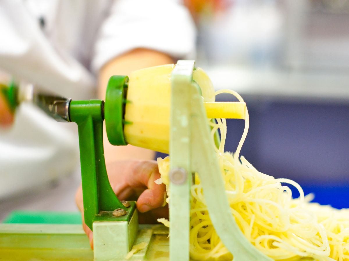 A person cutting vegetable noodles with a spiralizer.