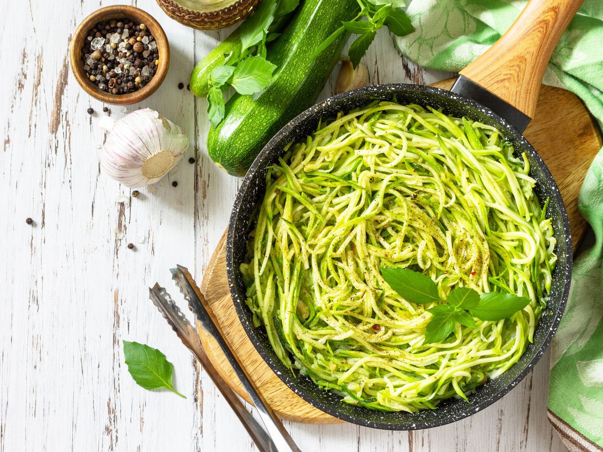 Zucchini noodles in a frying pan with herbs and spices.