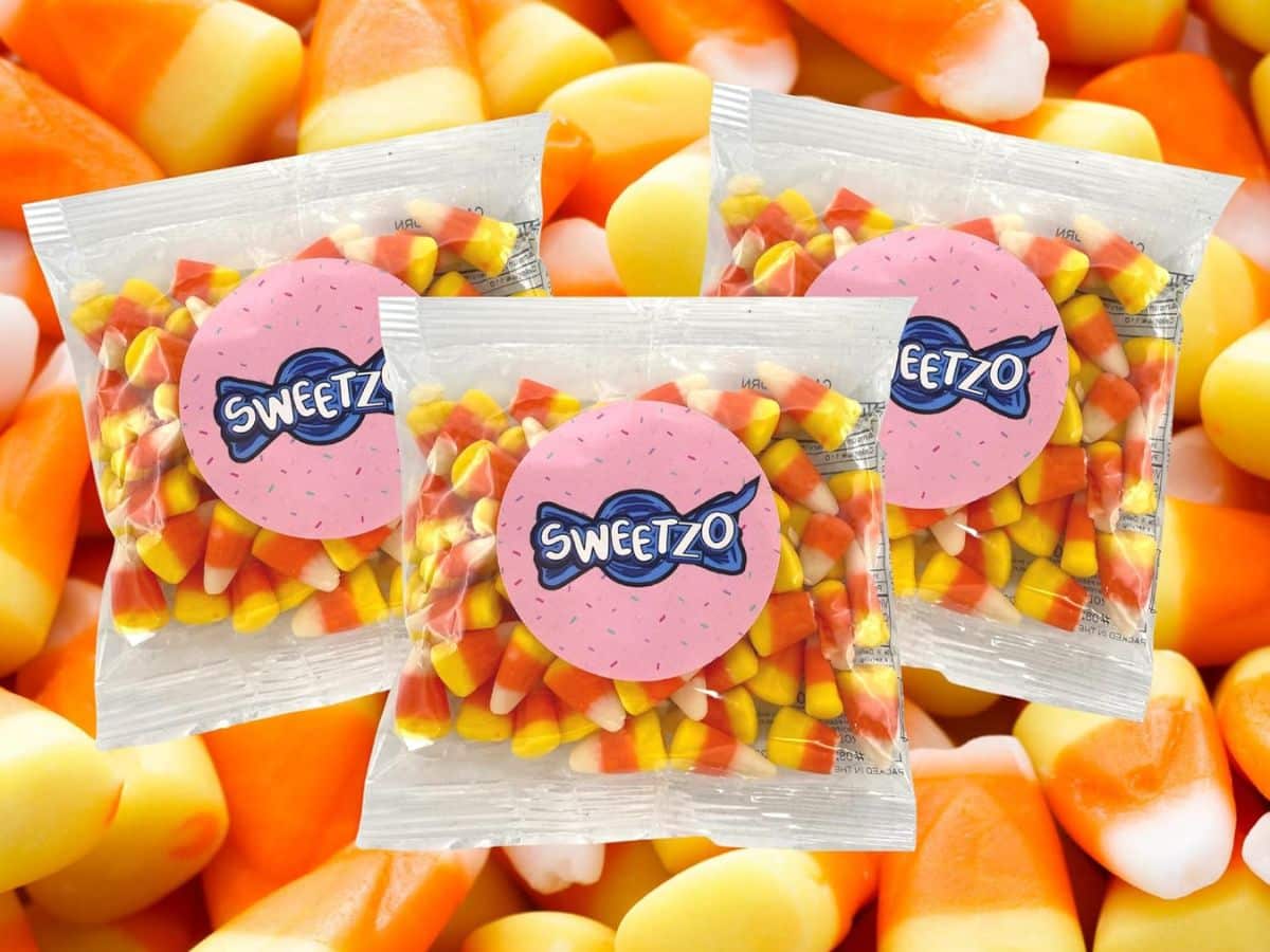 Three bags of alpha-gal friendly candy corn sitting on top of a pile of candy corn.