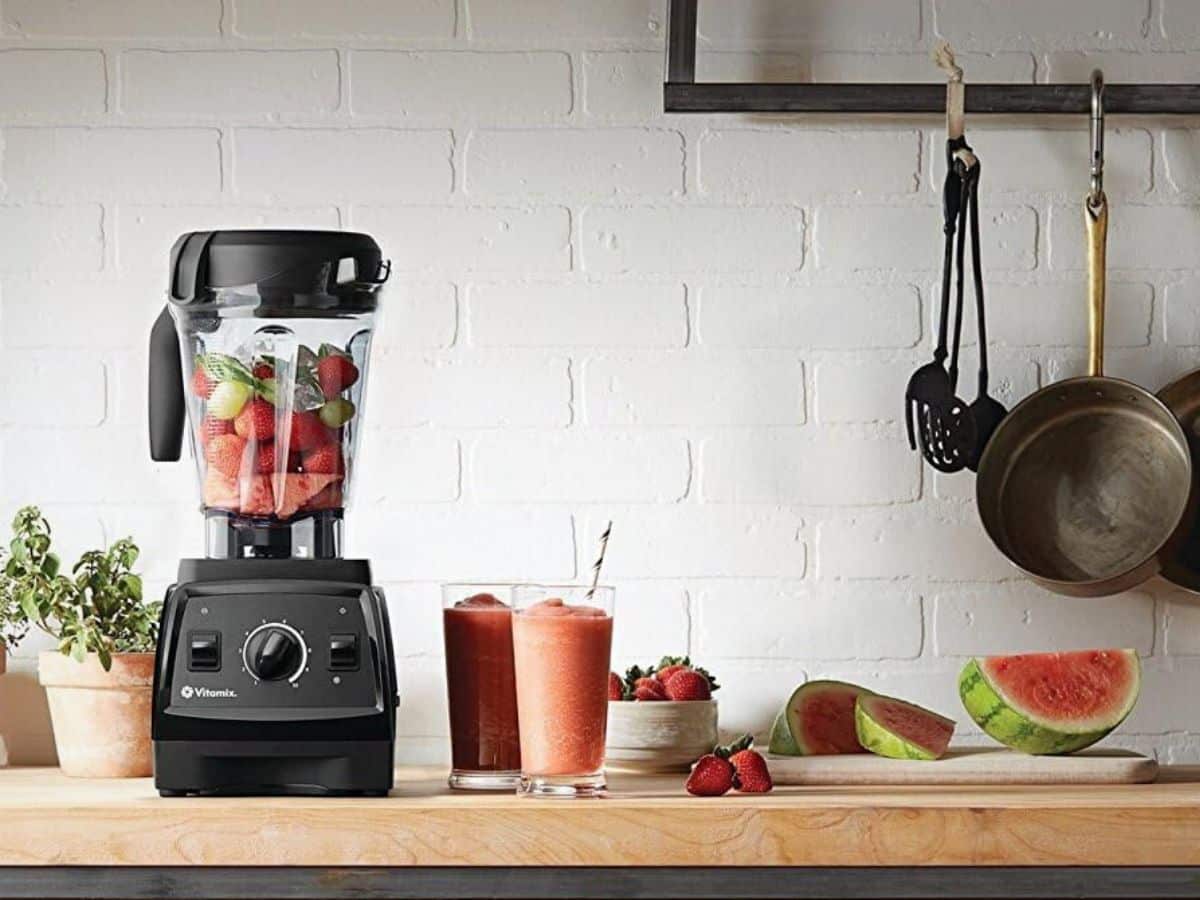 A Vitamix blender with fruit and vegetables on a countertop.