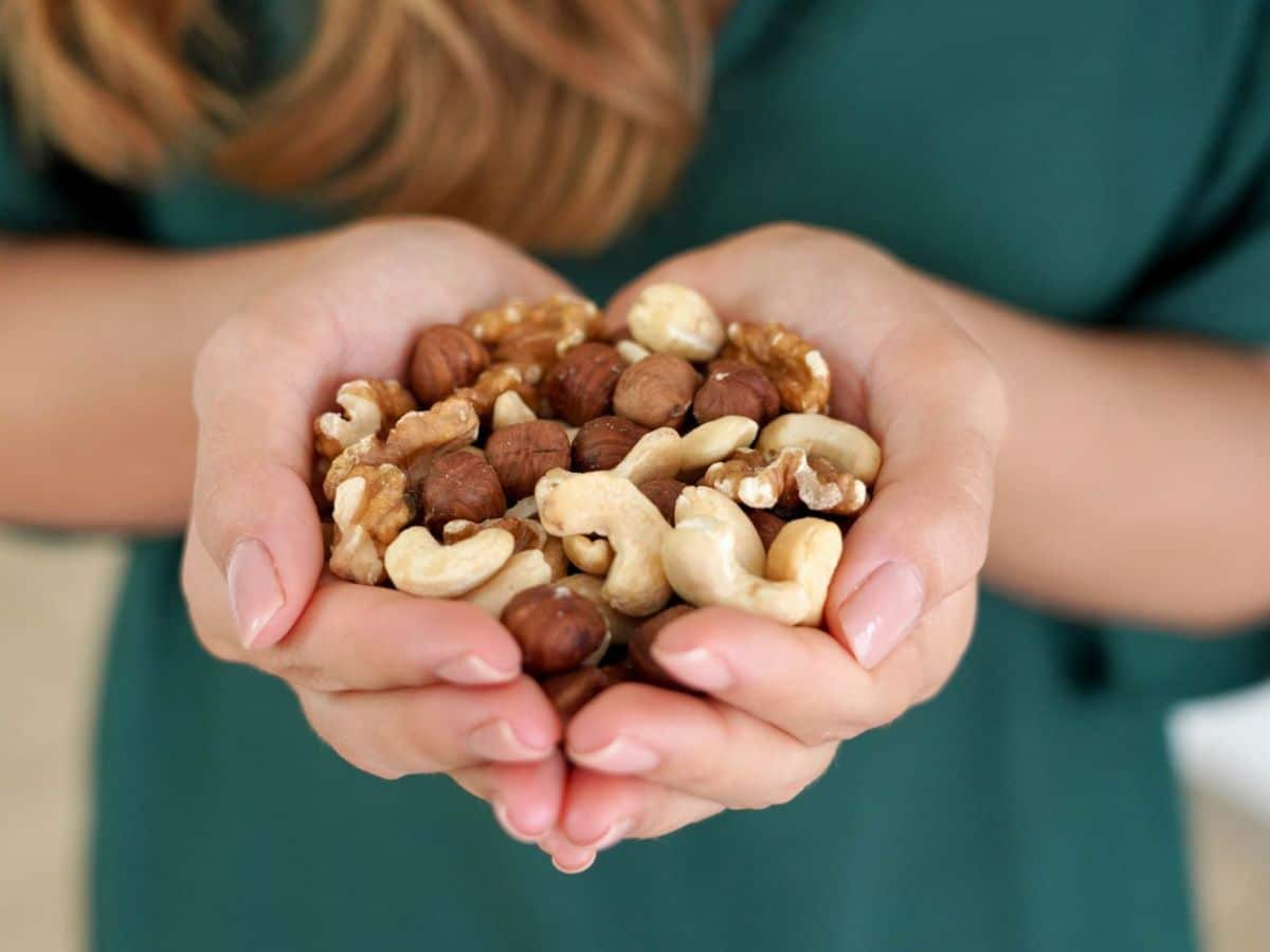 A woman holding an assortment of nuts in her hands.