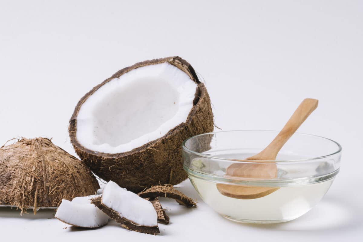 Coconut oil and a wooden spoon on a white background.