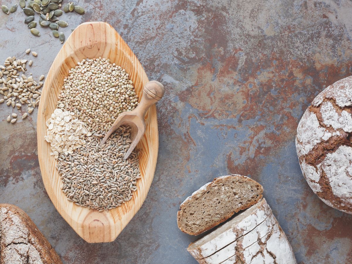 A wooden bowl with seeds and bread on it.