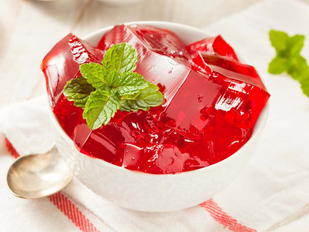 Red Jello in a white bowl with a mint leaf.