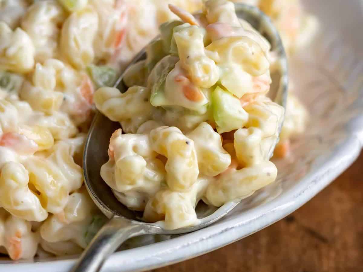 A spoonful of macaroni salad in a white bowl.