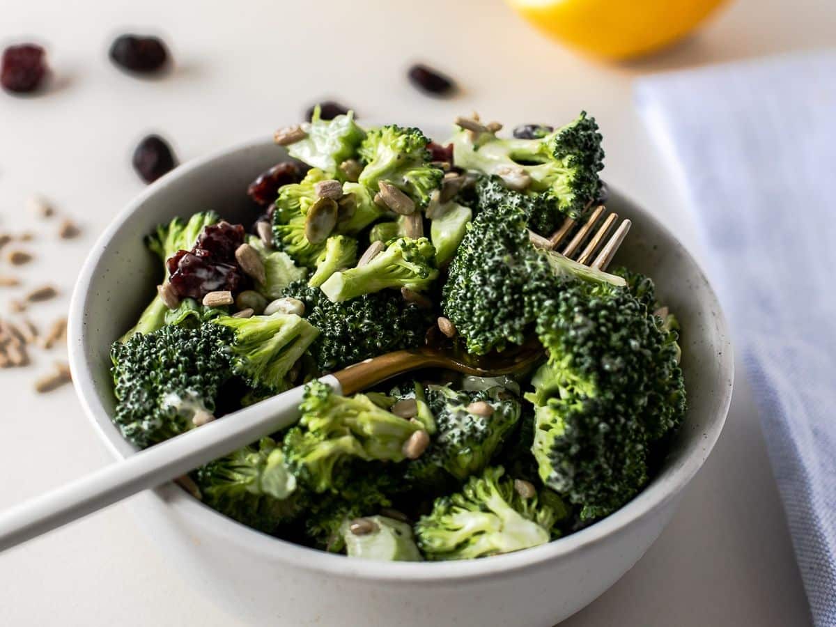 A bowl of broccoli salad with cranberries and sunflower seeds.
