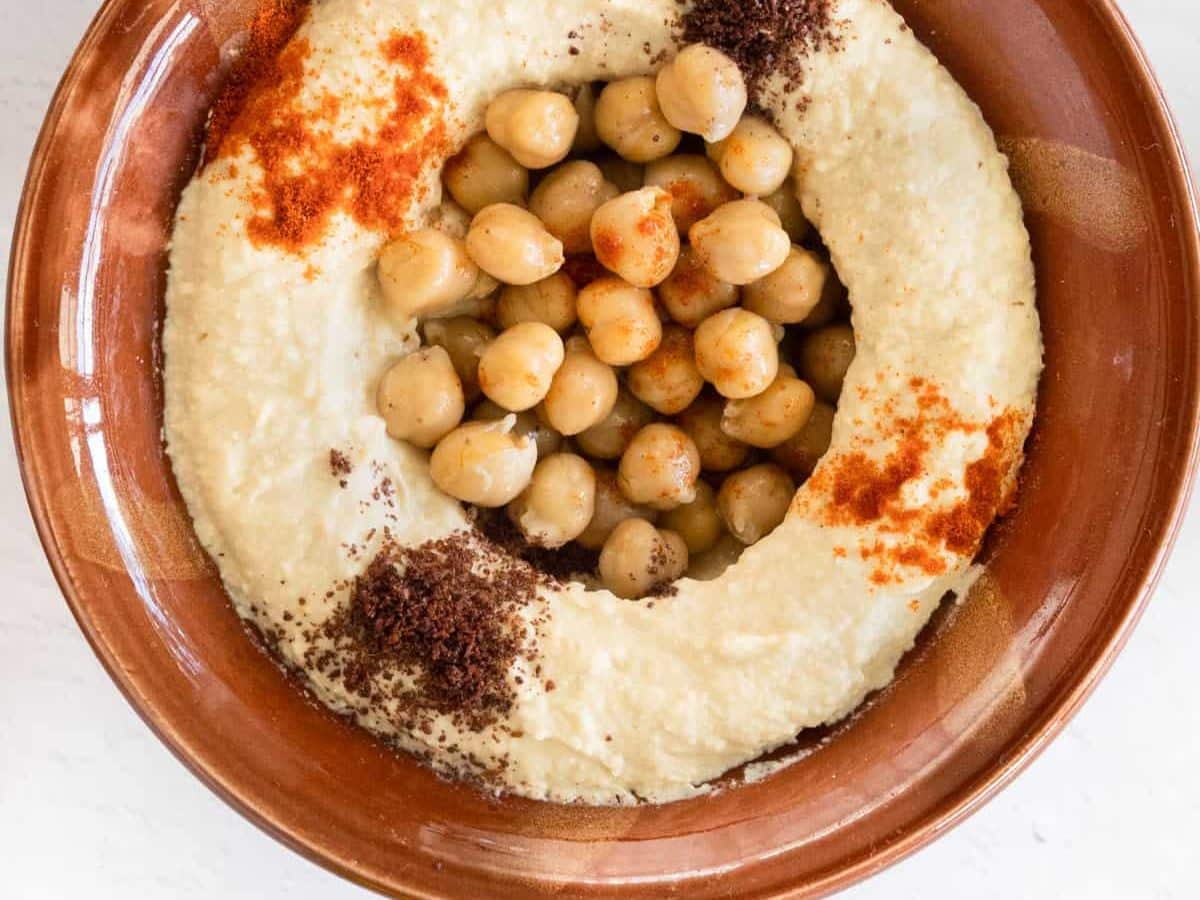 A bowl of hummus with chickpeas and spices.
