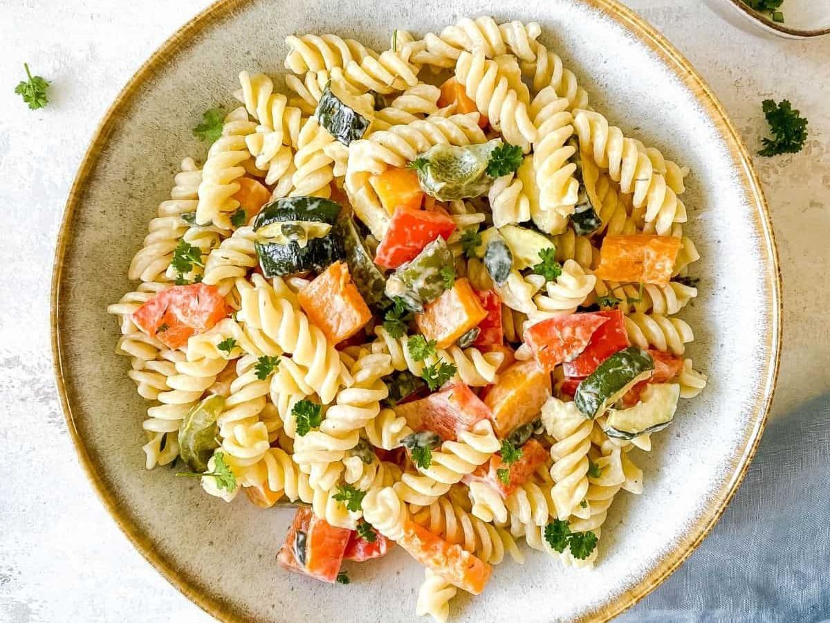 A bowl of pasta with vegetables and parsley.