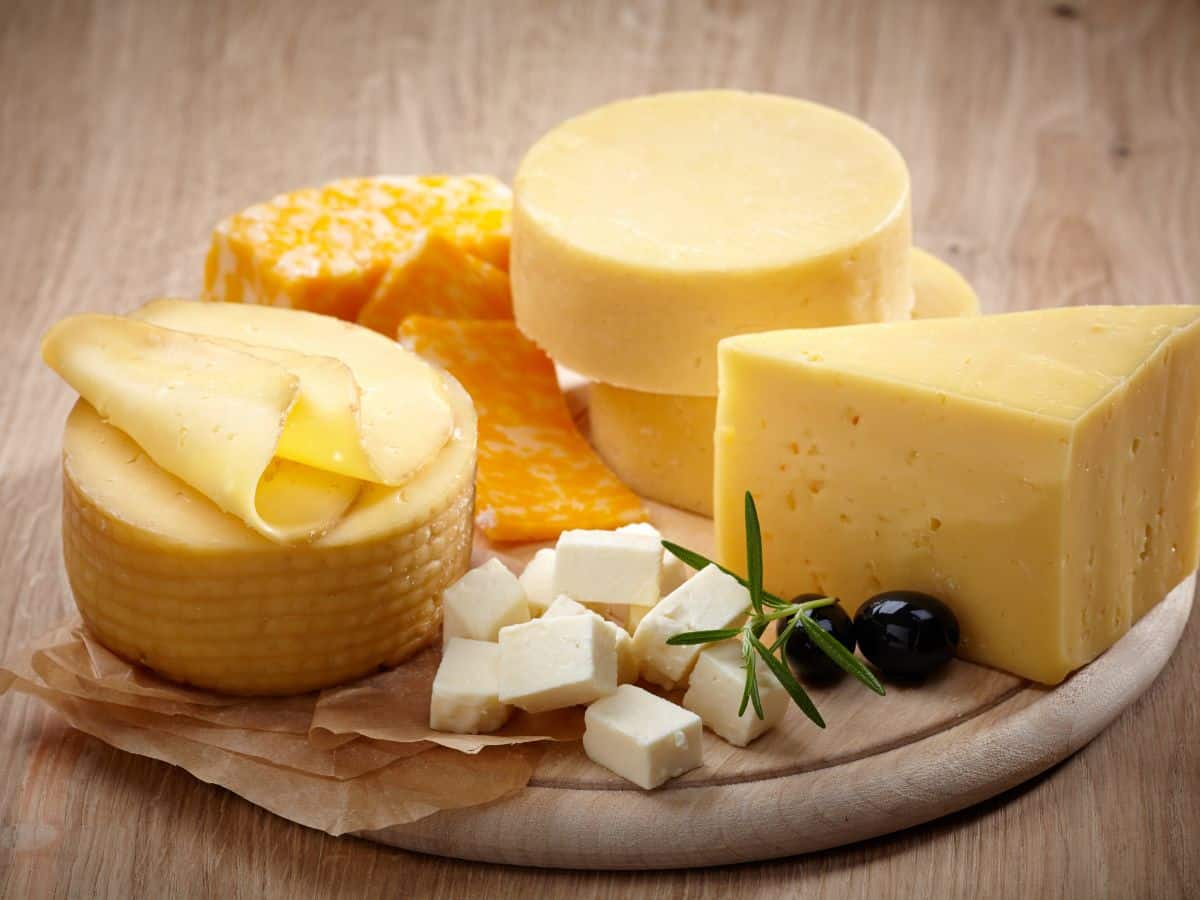 Various types of cheese on a wooden plate.