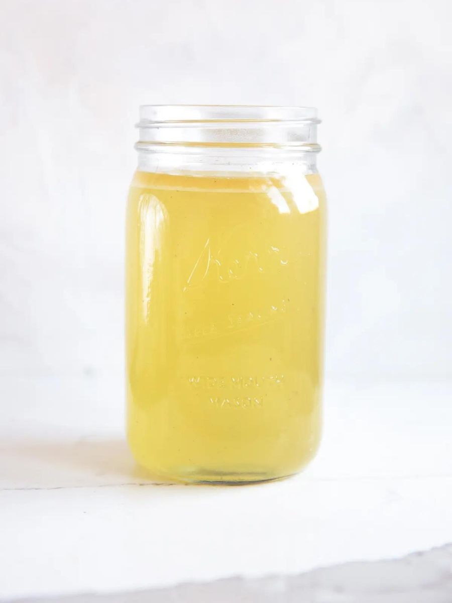 A jar of turkey stock sitting on a white surface.