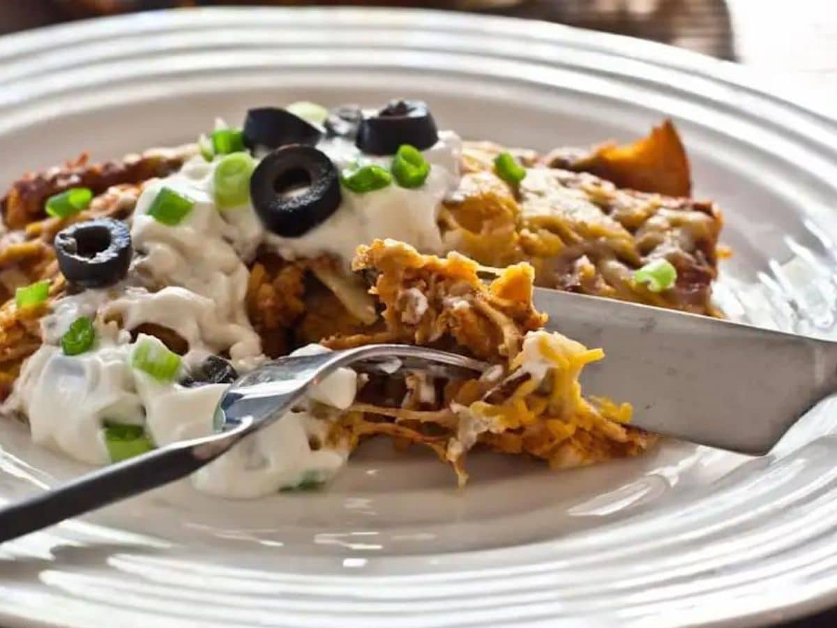 Turkey enchiladas with sour cream and olives on a plate.