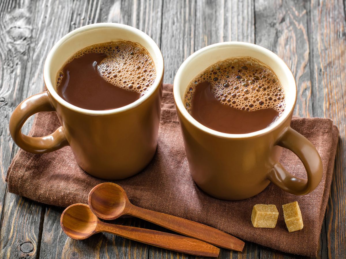 Two mugs of hot chocolate on a wooden table.