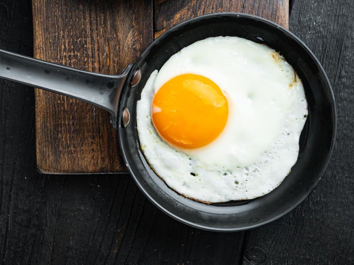 A fried egg in a cast iron frying pan on a wooden table.