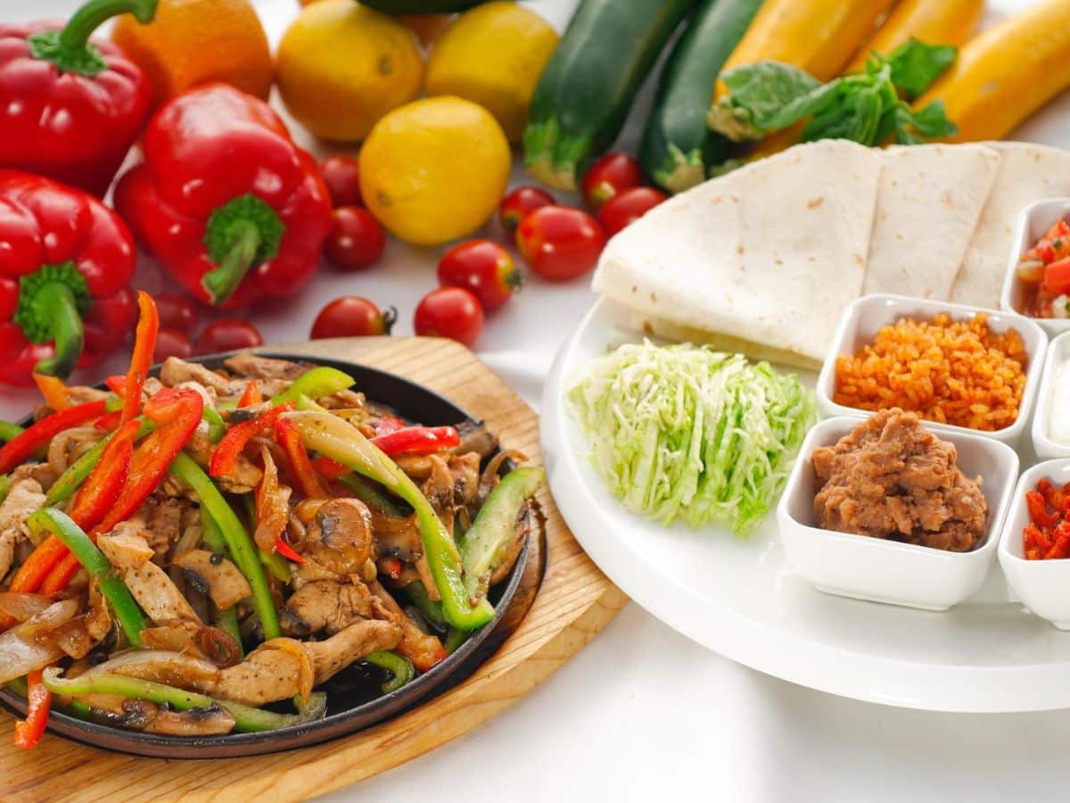 A plate of chicken fajitas with vegetables and tortillas, perfect for your next taco bar gathering.