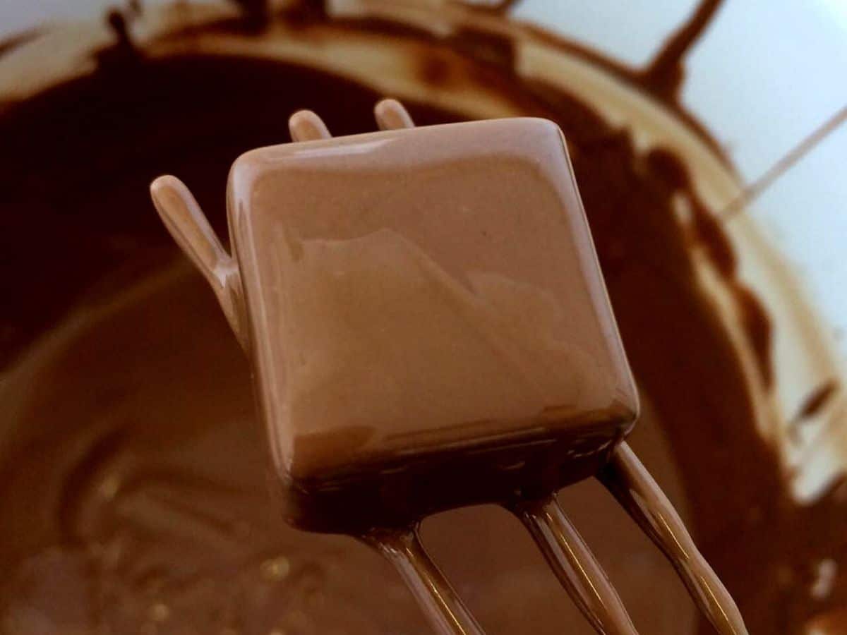 Dipping caramel squares into melted chocolate.