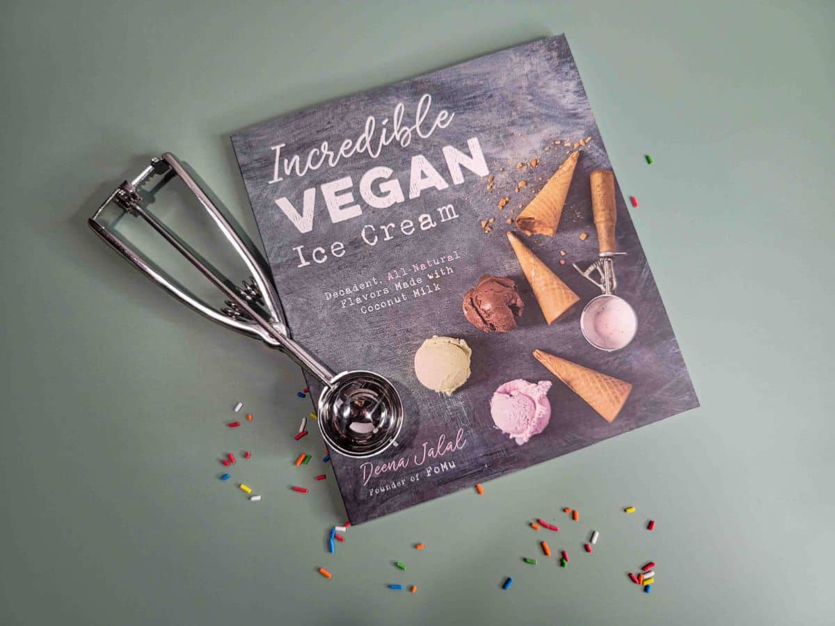 A copy of the Incredible Vegan Ice Cream cookbook with an ice cream scoops.