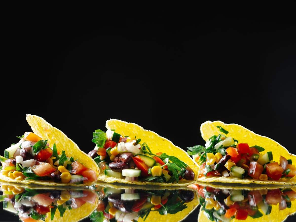 Three flavorful vegetarian tacos on a black background.