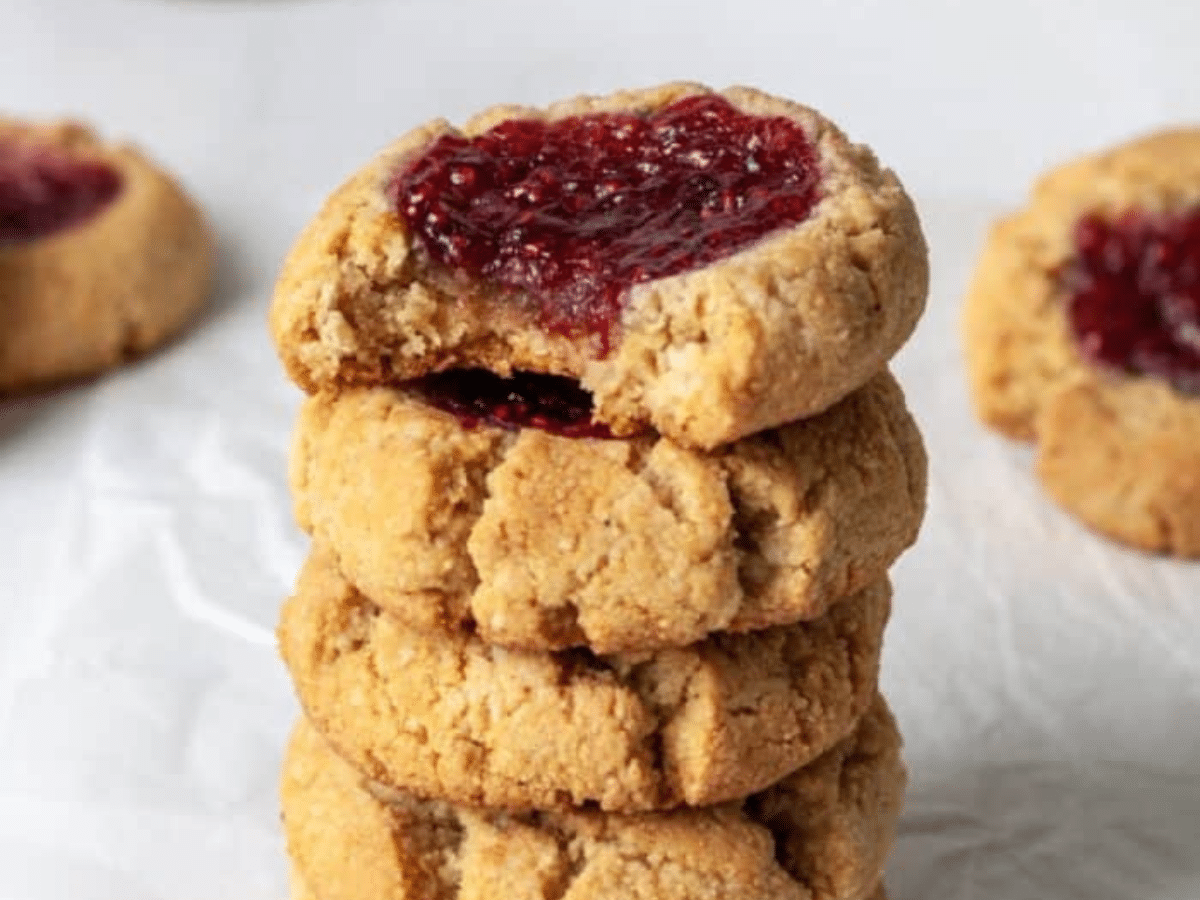 A stack of vegan thumbprint cookies with jam on top.