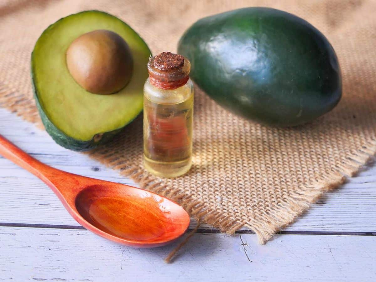 Avocado oil and a wooden spoon on the table.