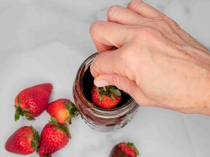 Learn how to make chocolate covered strawberries by watching this person expertly pour rich, melted chocolate over a fresh batch of juicy strawberries.