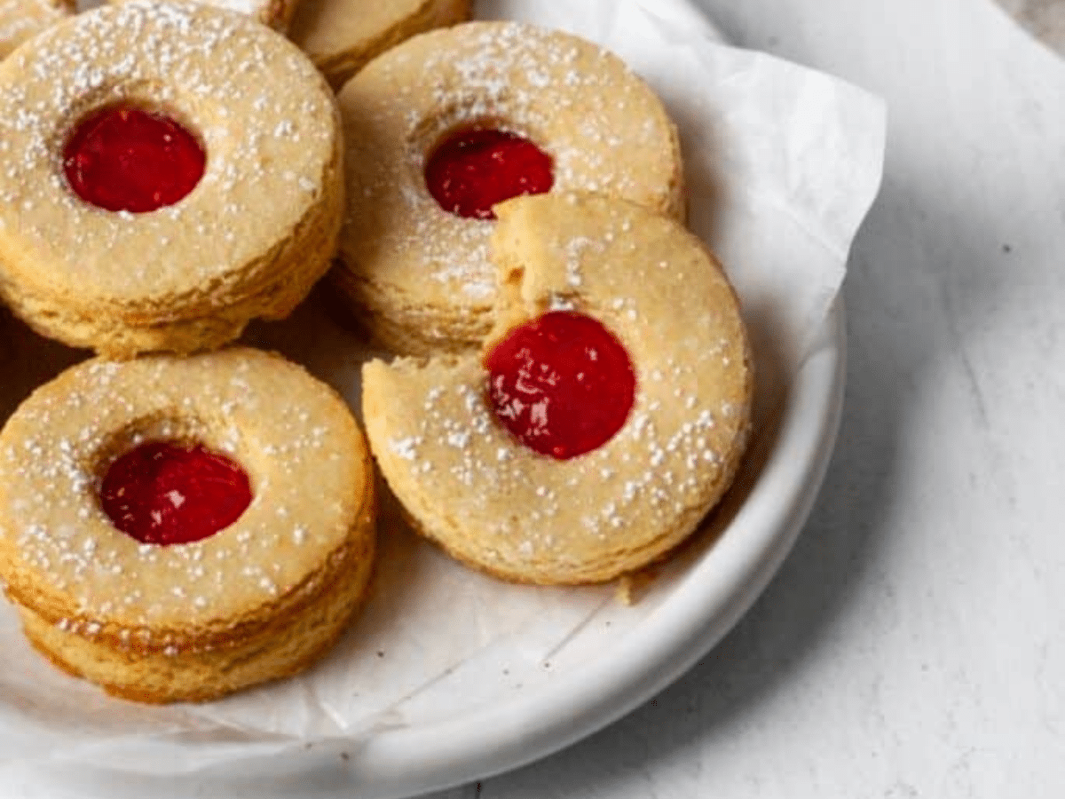 A plate of vegan thumbprint cookies with a cherry in the middle.