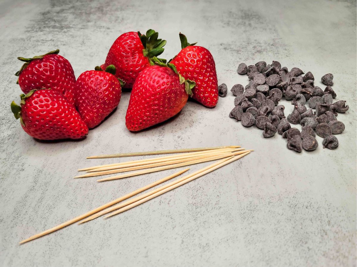The ingredients needed to make chocolate covered strawberries: fresh strawberries and chocolate.